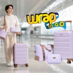 Viajera con maleta rígida con ruedas y equipaje a juego en una terminal de aeropuerto